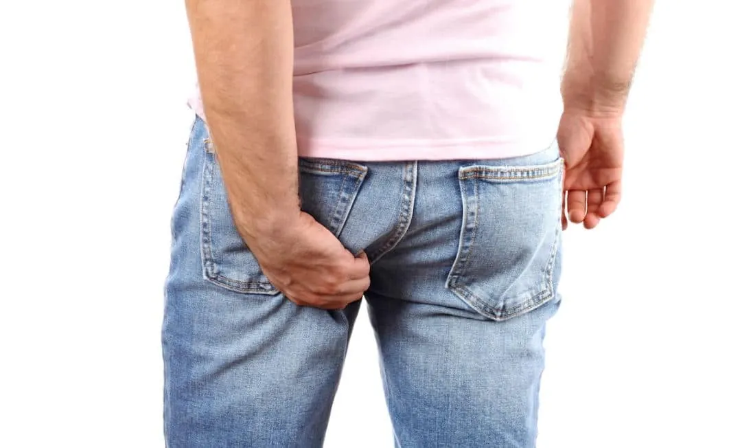 Person scratching from anal itching (pruritus ani)