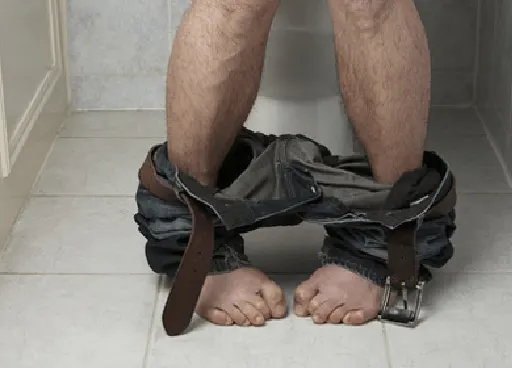 Person sitting on a toilet with hemorrhoid discomfort